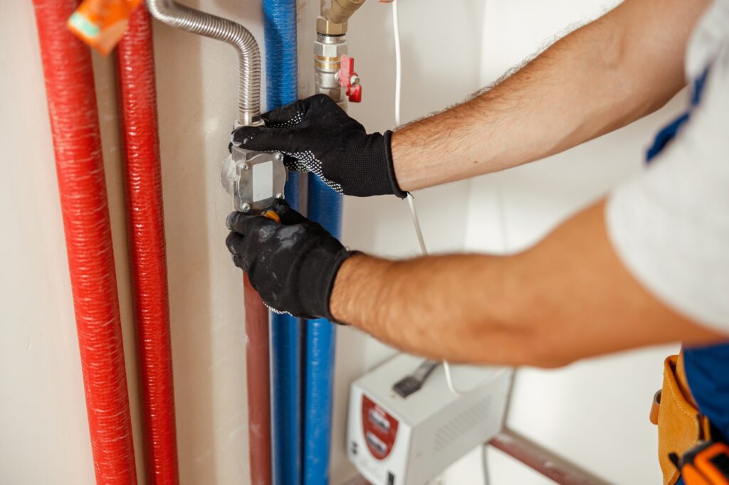 Closeup of plumber hands fixing pipes while installing heating system in apartment