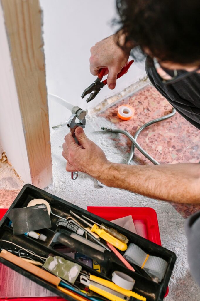 Plumber tightening pipe with wrench and pliers in heating installation